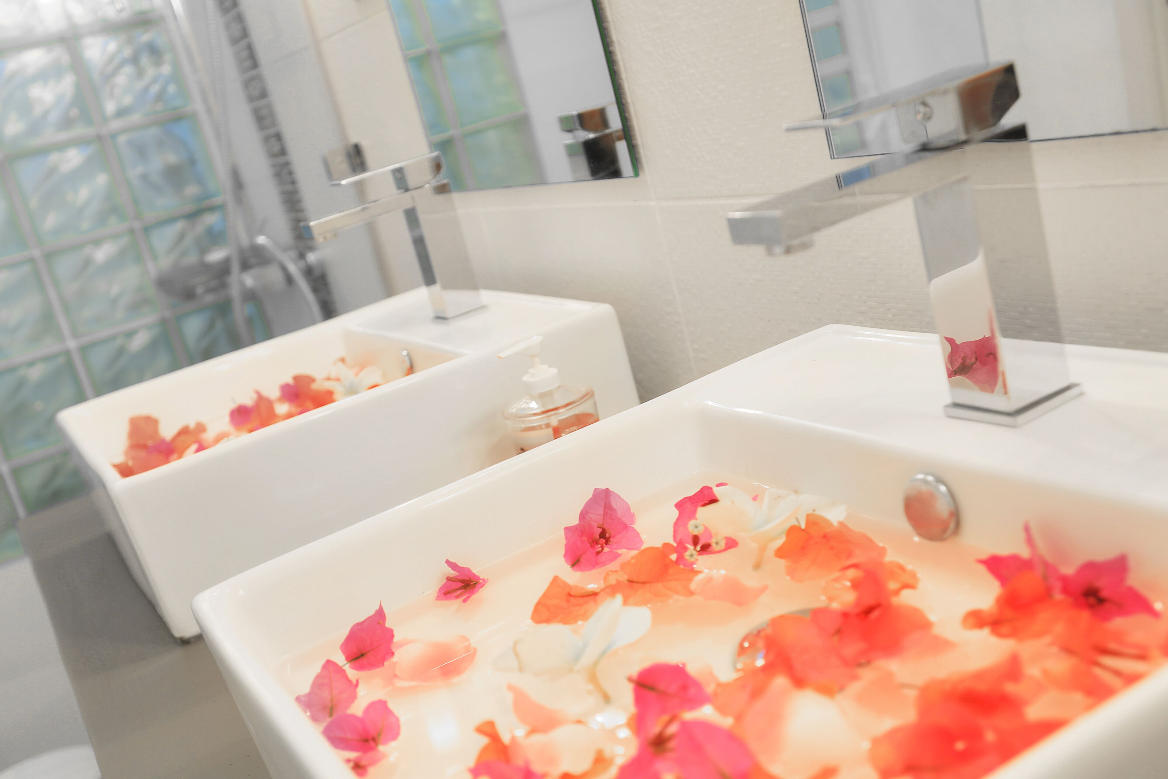 A bathroom with two white sinks and a bathtub filled with rose petals.