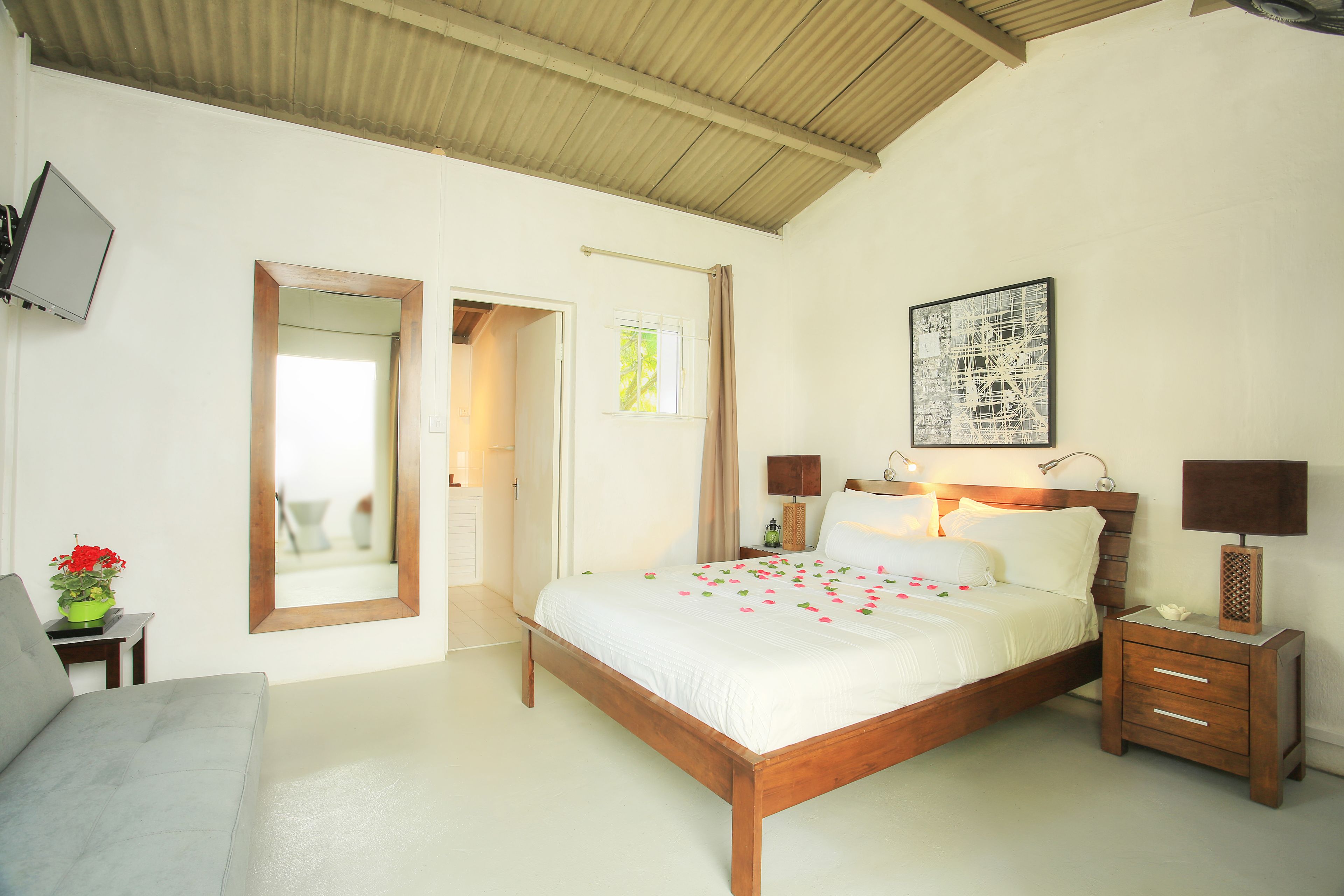 Een slaapkamer met een houten bed, nachtkastjes, een televisie en een deur naar een andere kamer.