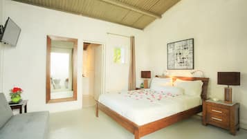 Een slaapkamer met een houten bed, nachtkastjes, een televisie en een deur naar een andere kamer.