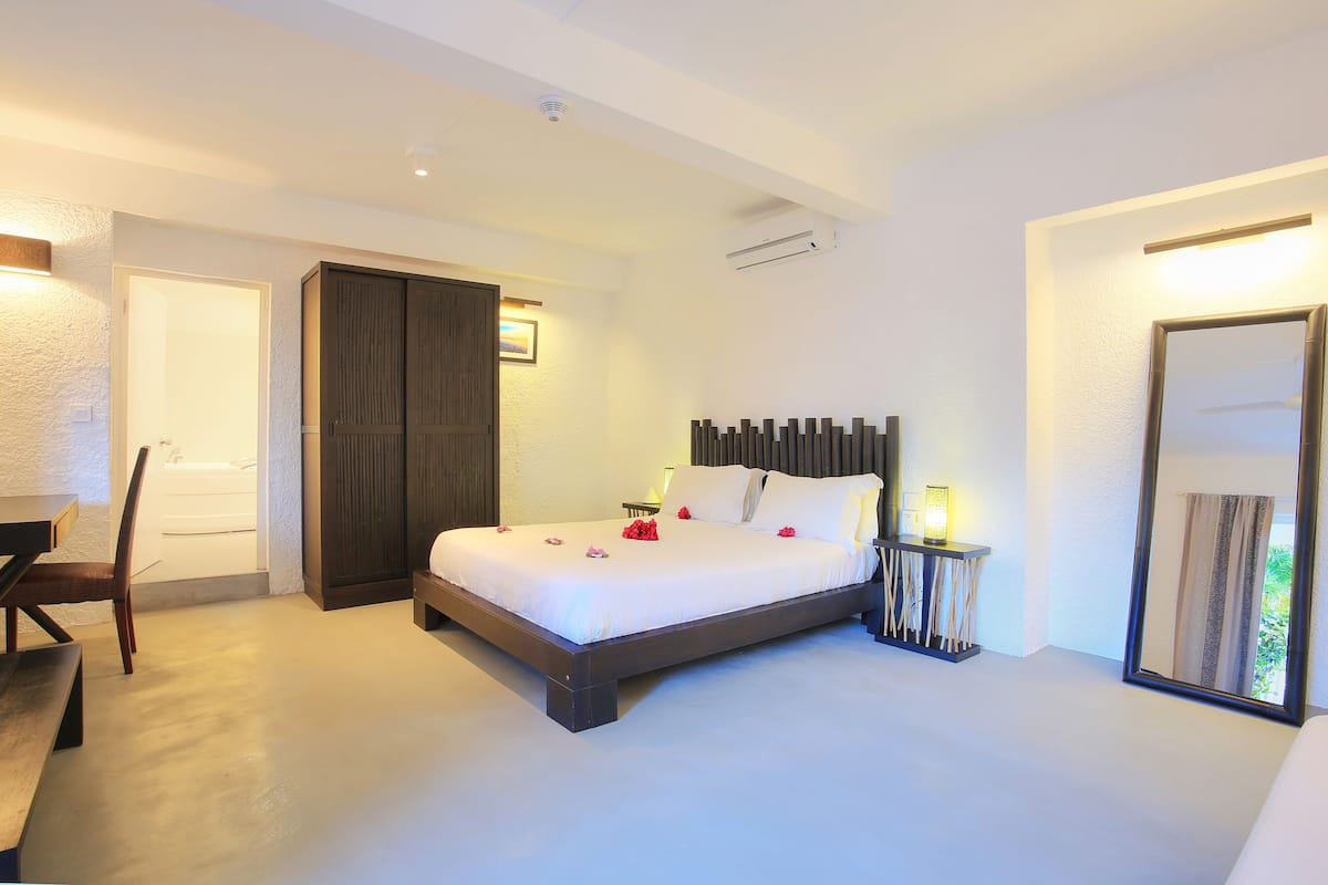 A bedroom with a large bed, bedside tables, a chair, and a wardrobe.