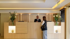 A reception desk with a wooden finish, two vases with flowers, and a sign indicating the exit.
