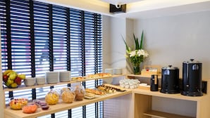A buffet setup with various food items, plates, and cups, and coffee machines. - M Concept Hotel (Buenos Aires)