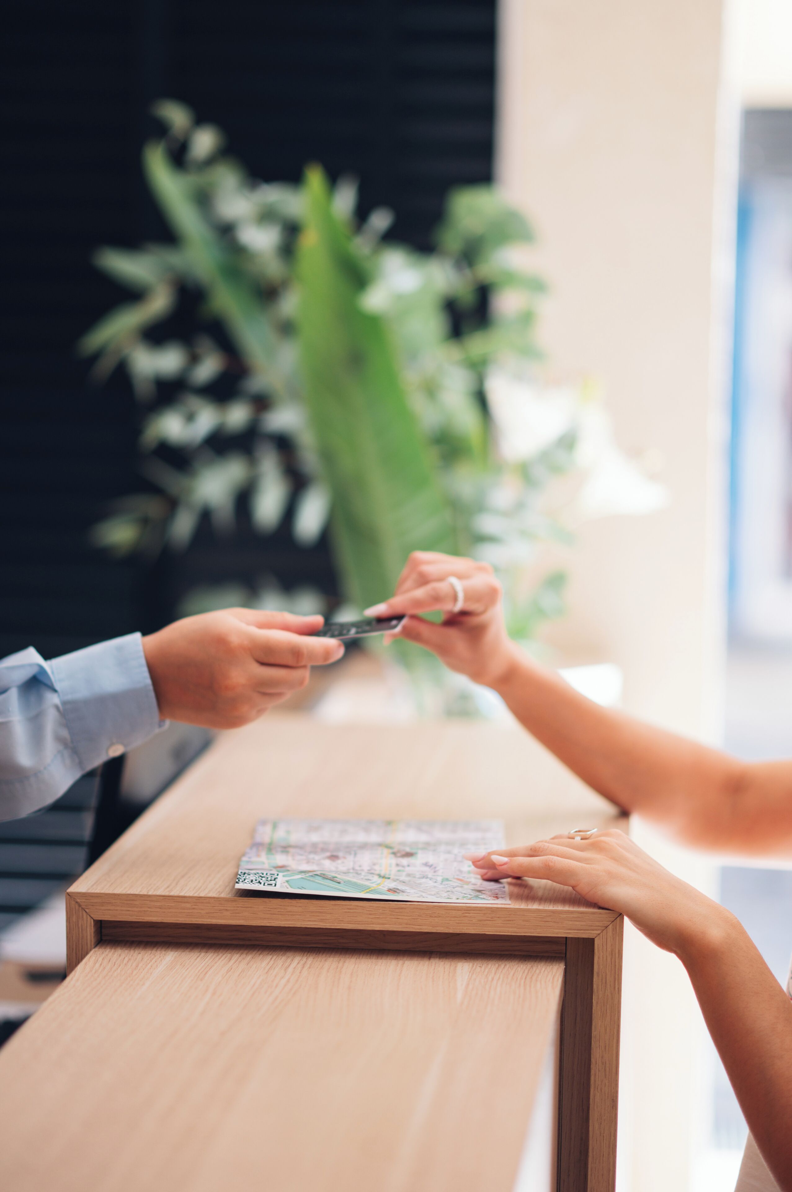 Un comptoir d’accueil en bois, avec une carte et une personne tenant un smartphone.