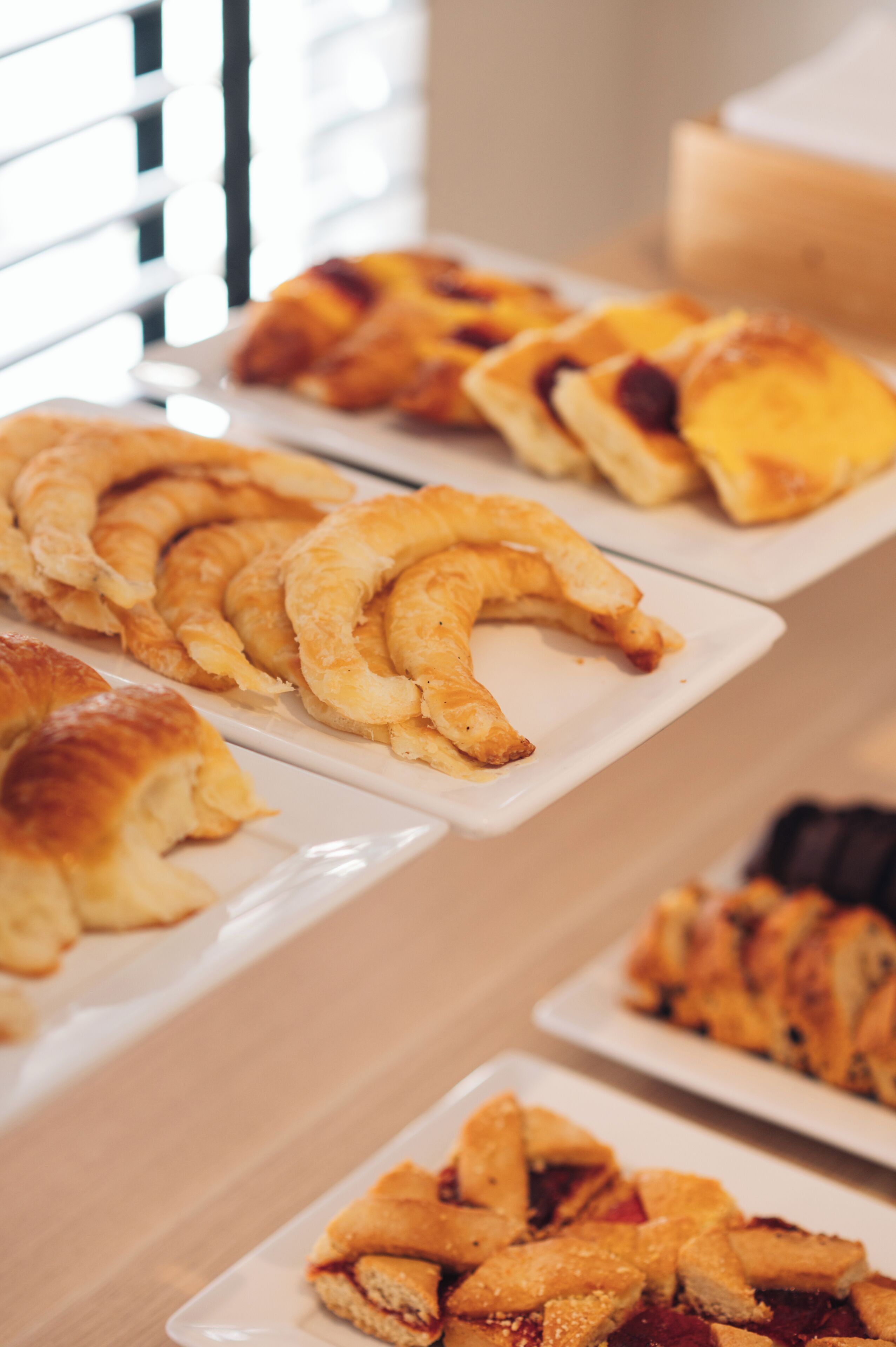 A table with various pastries arranged on white plates.
