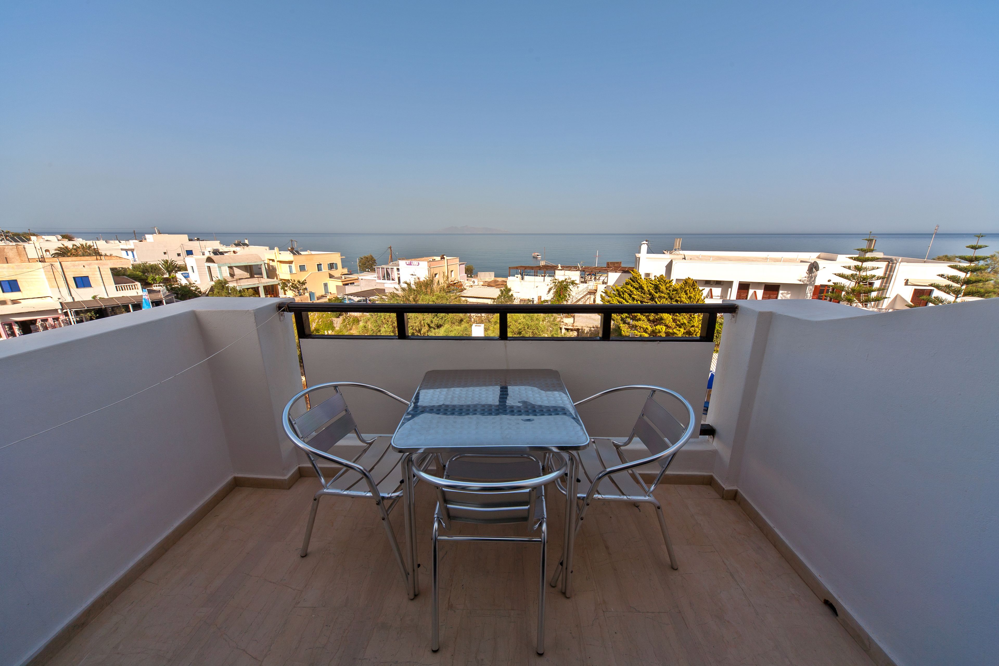 Un balcón con una mesa y sillas, con vistas a la ciudad y al mar.