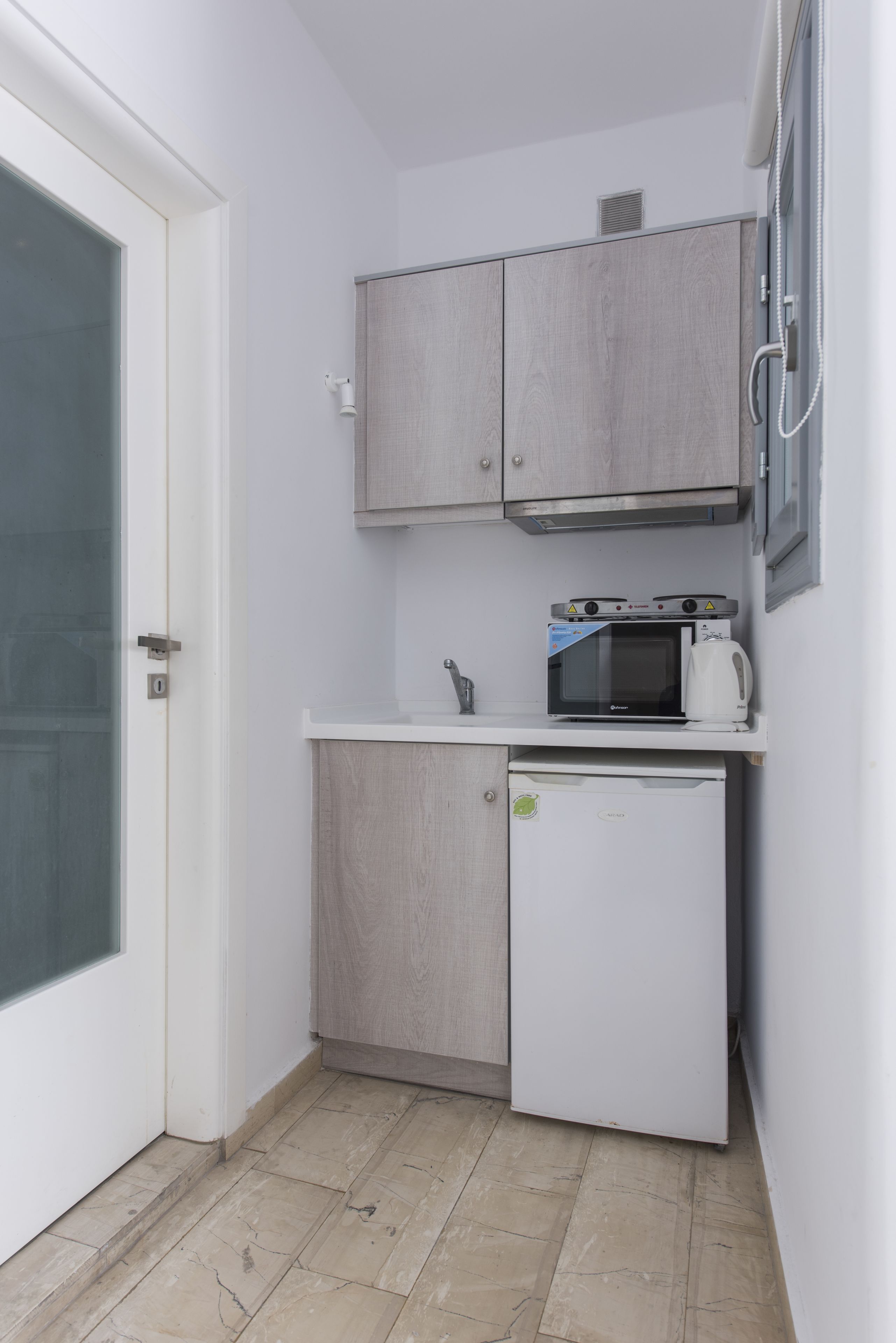 Una cocina compacta equipada con microondas, hervidor y un refrigerador pequeño.