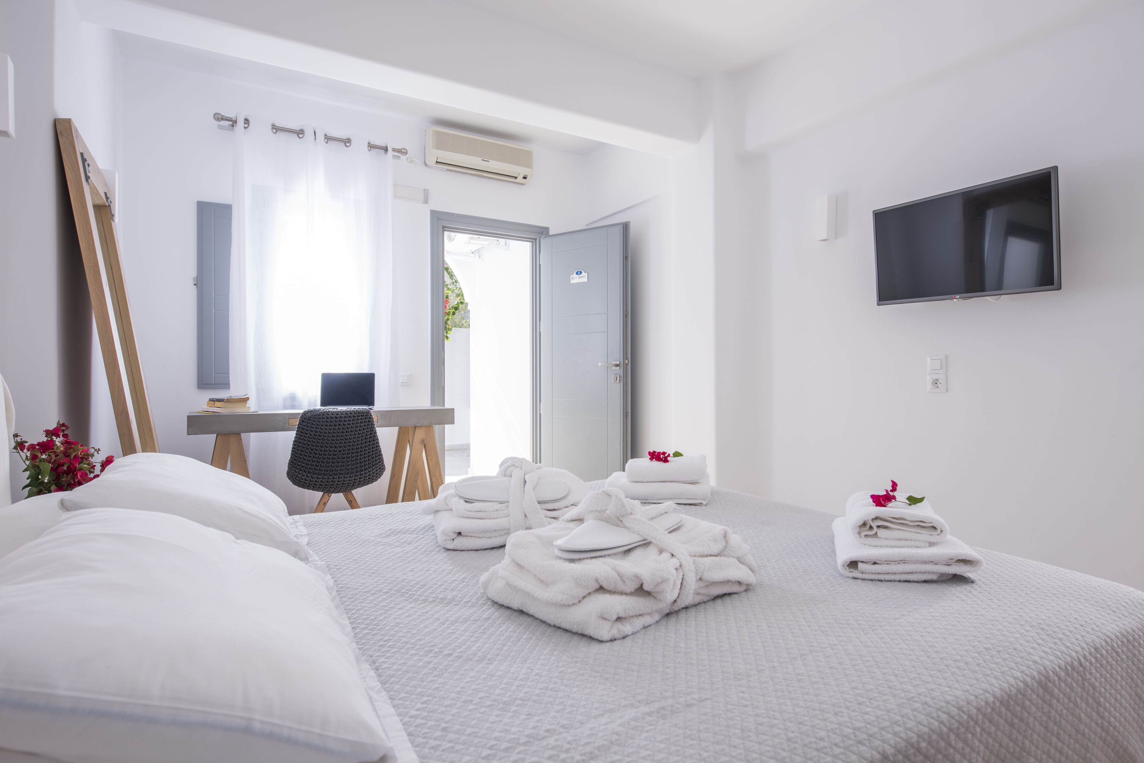 A hotel room with a bed, a desk, a chair, and a TV.