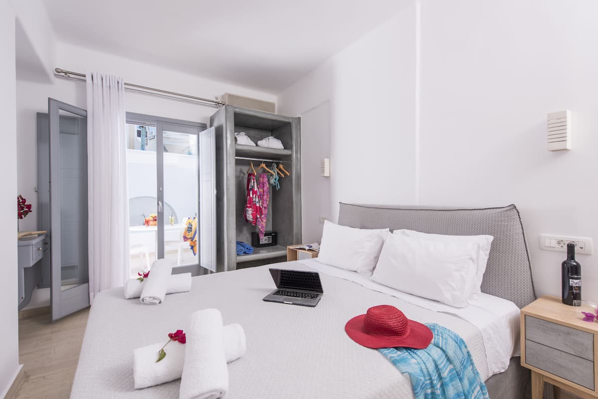 A hotel room with a bed, a laptop, a red hat, and a wardrobe.
