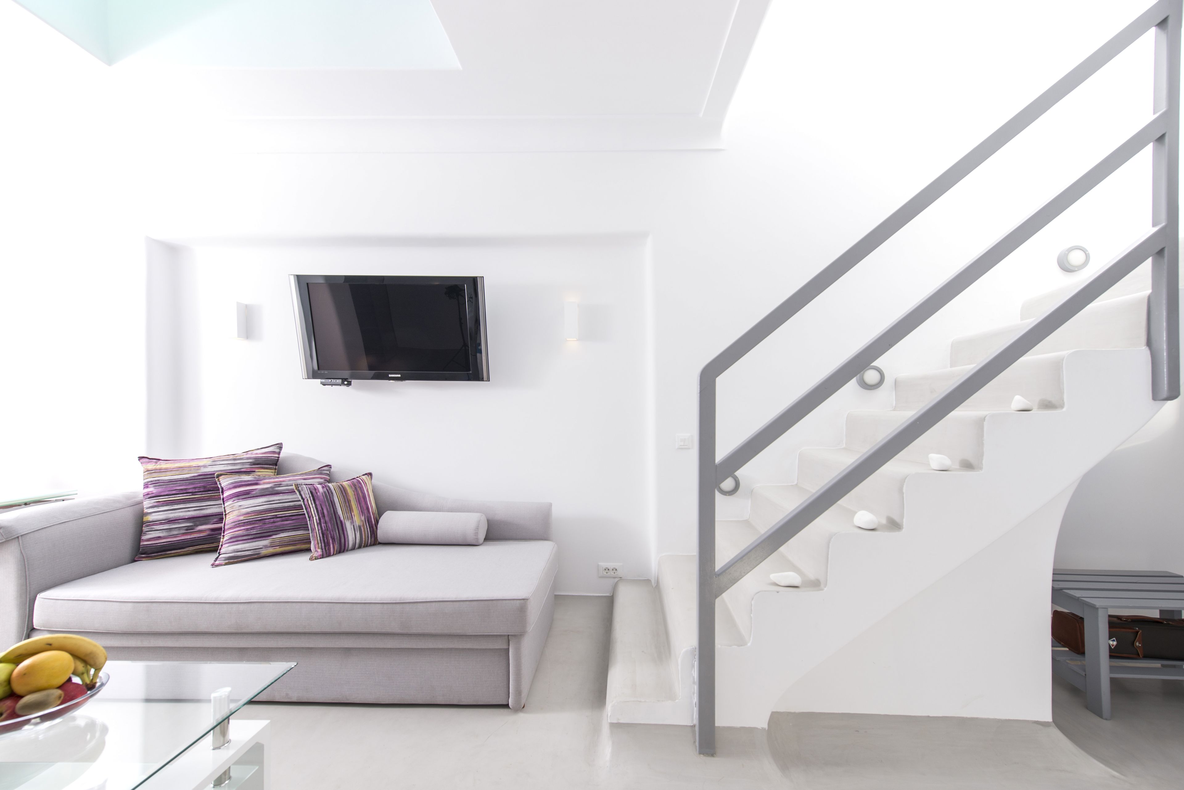 Ein modernes Wohnzimmer mit einer Couch, einem Flachbildfernseher und einer Treppe.