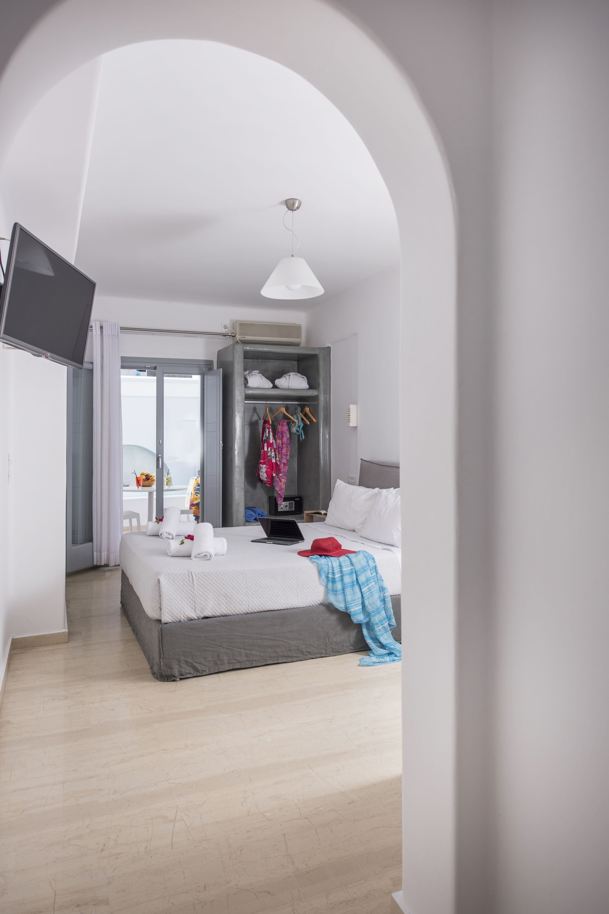 A modern hotel room with a bed, a desk, a wardrobe, and a TV.