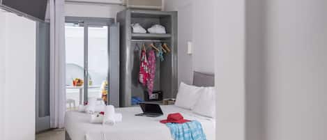 A modern hotel room with a bed, a desk, a wardrobe, and a TV.