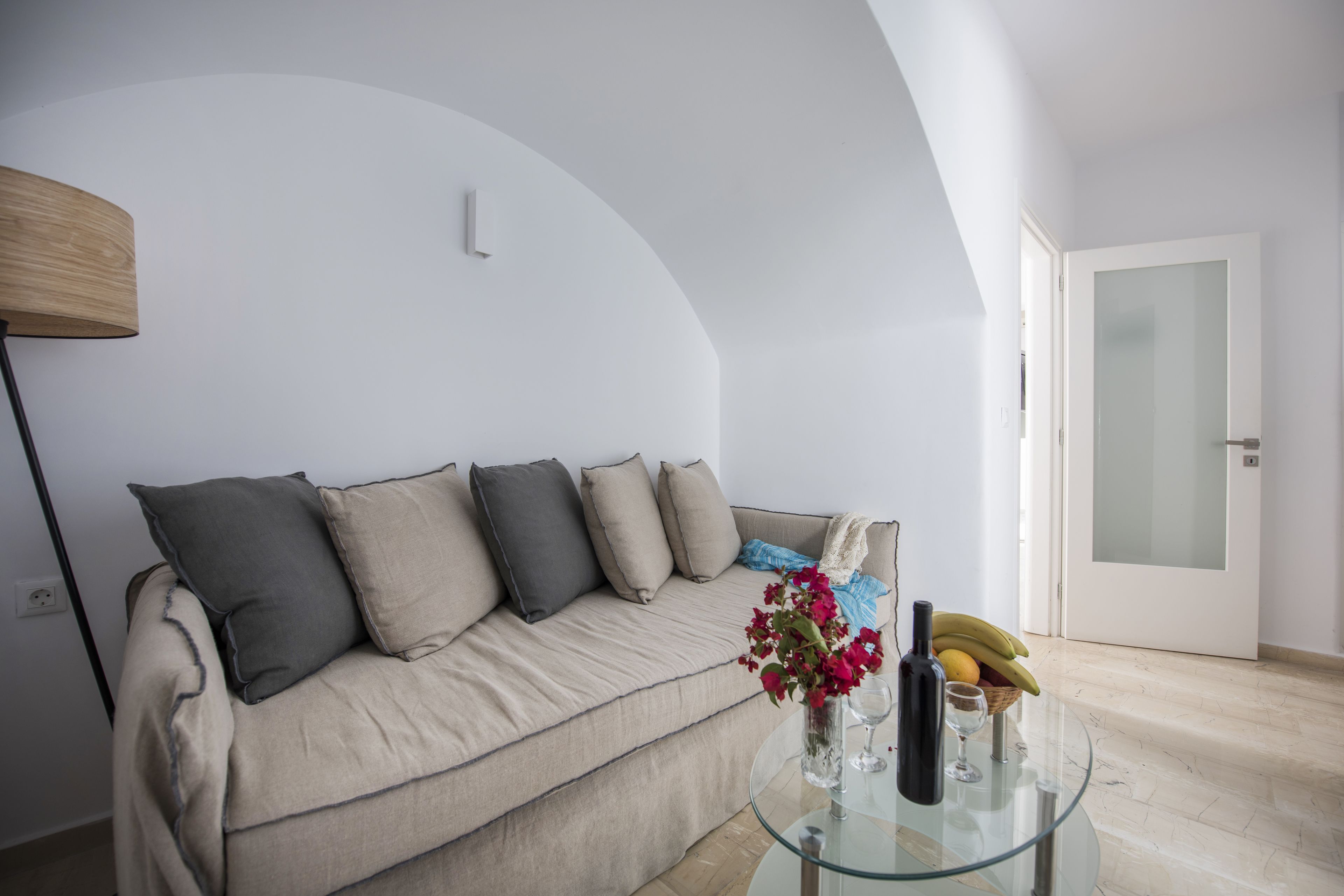Ein modernes Wohnzimmer mit einem beigefarbenen Sofa, einem Glastisch und einer Vase mit Blumen.