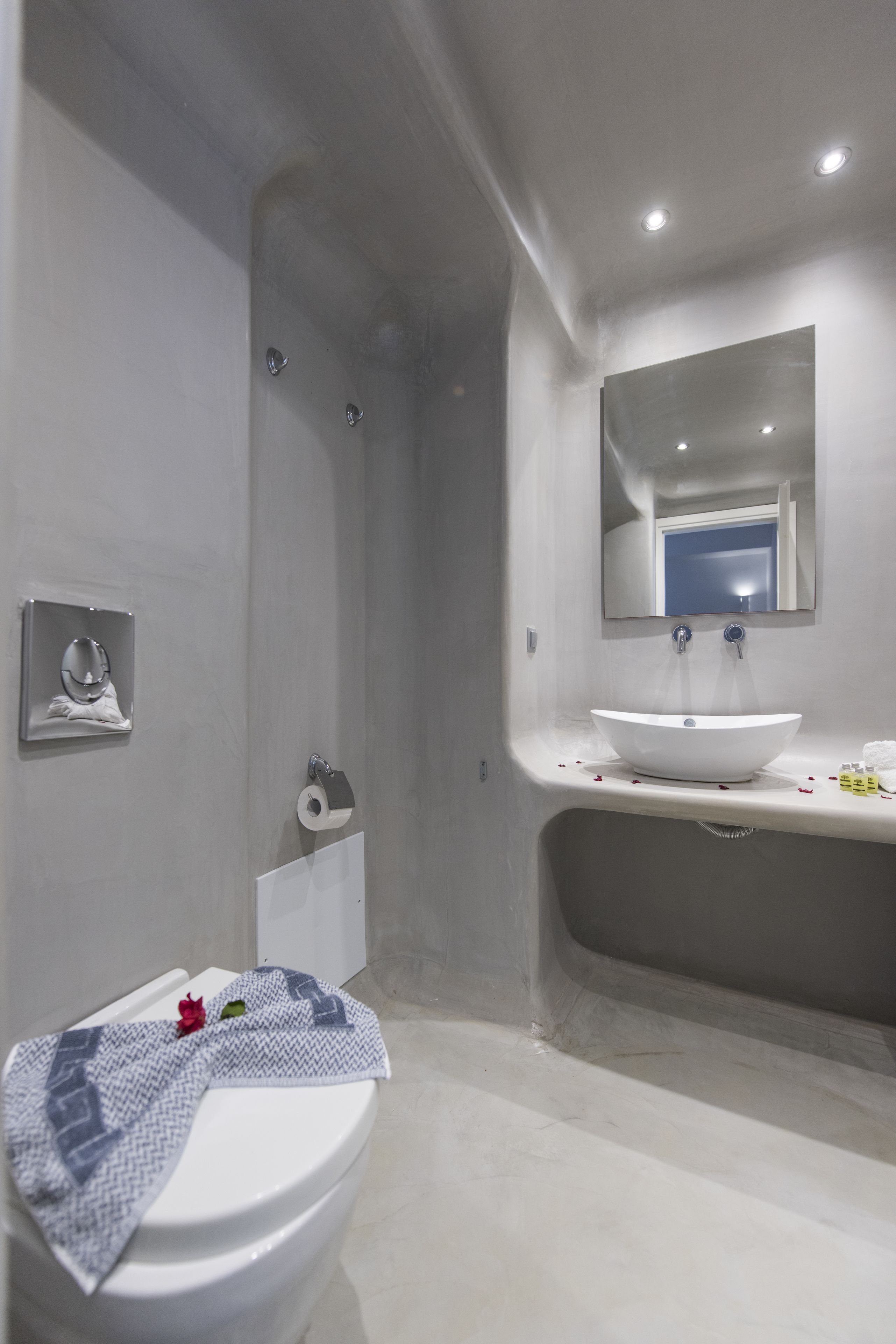 A modern bathroom with a white sink, mirror, and toilet.