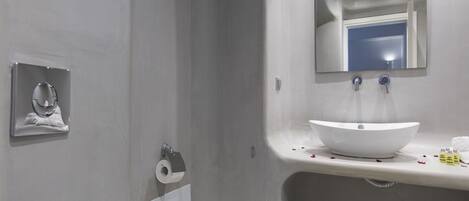 A modern bathroom with a white sink, mirror, and toilet.