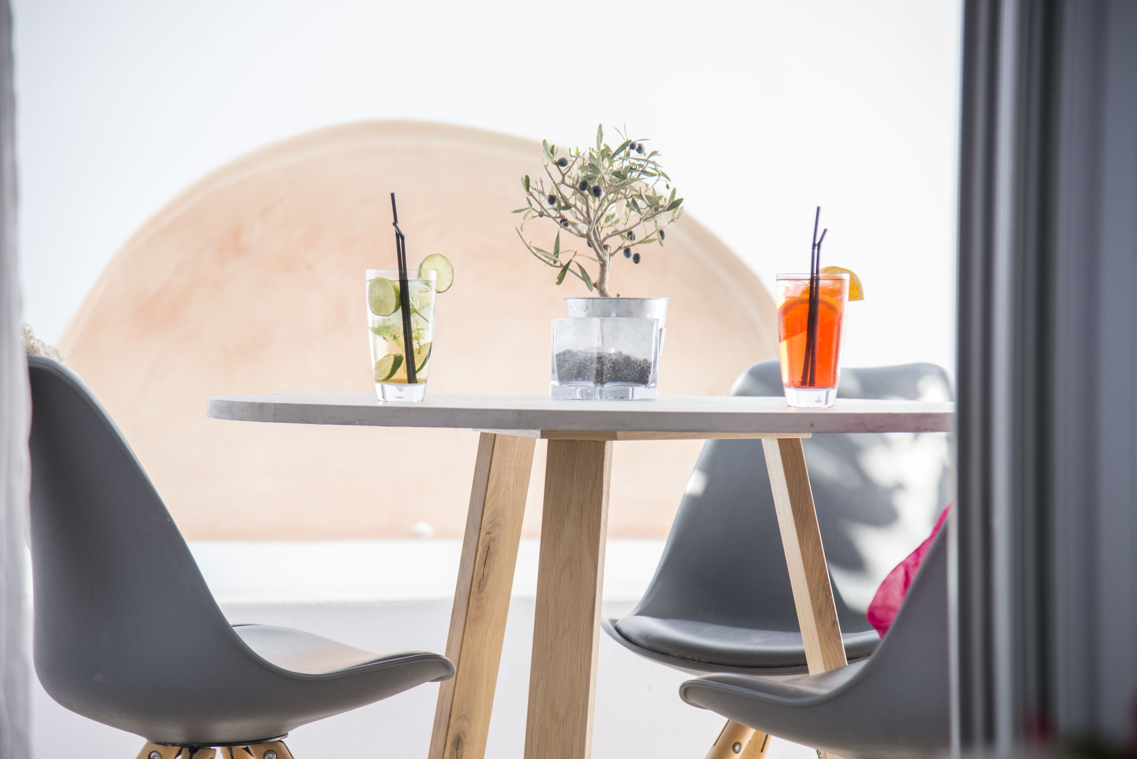 Une table avec deux chaises, une plante en pot et deux boissons avec des pailles.