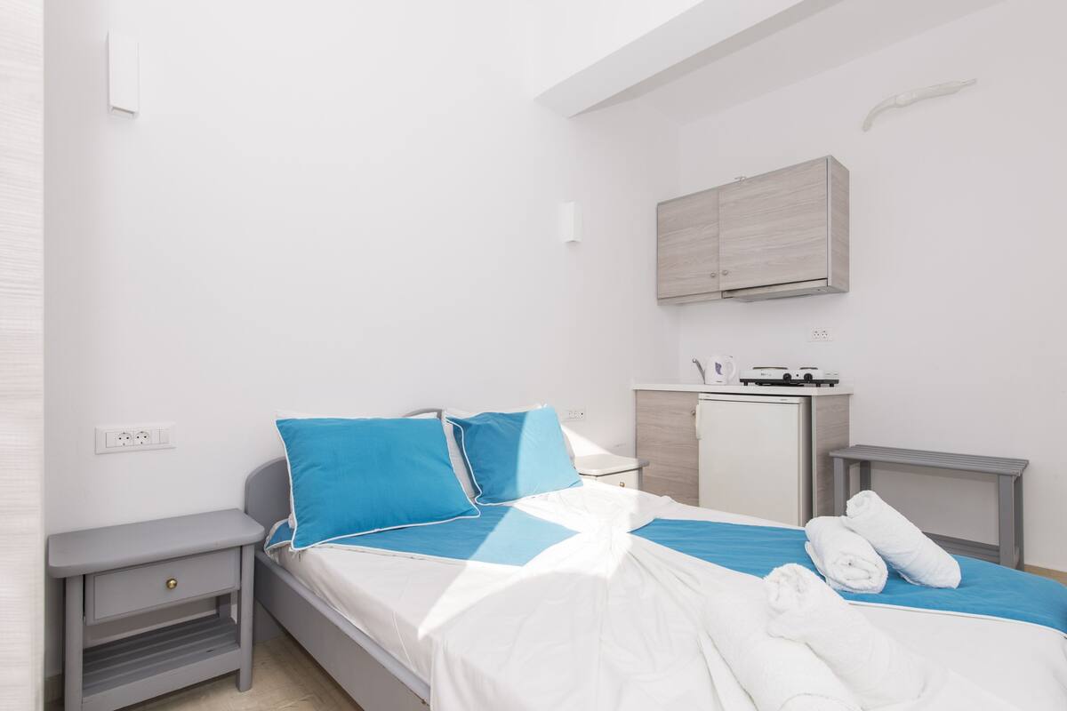 A modern bedroom with a bed, a nightstand, a small desk, and a built-in wardrobe.