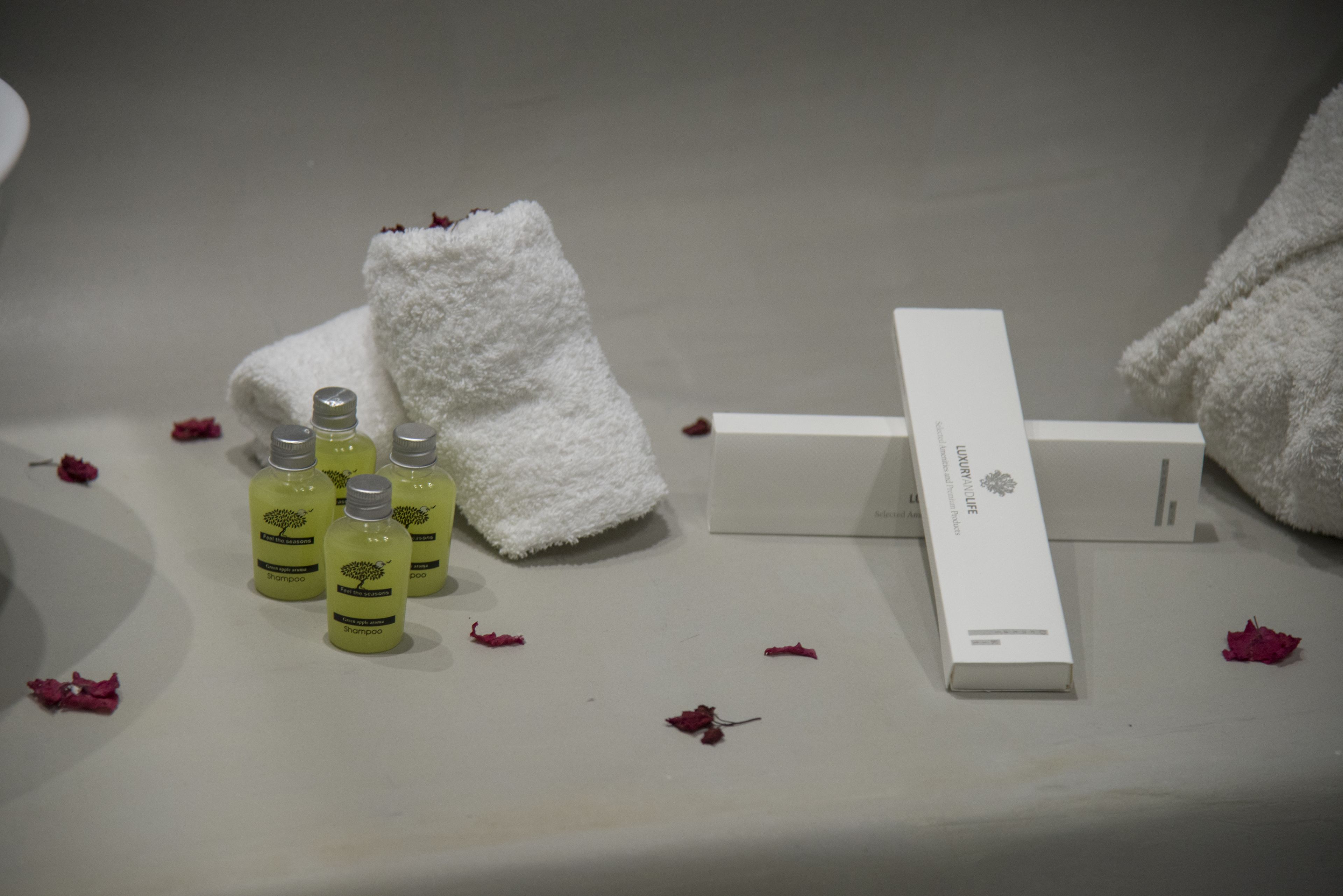 A bathroom with toiletries including shampoo bottles, a towel, and a box.