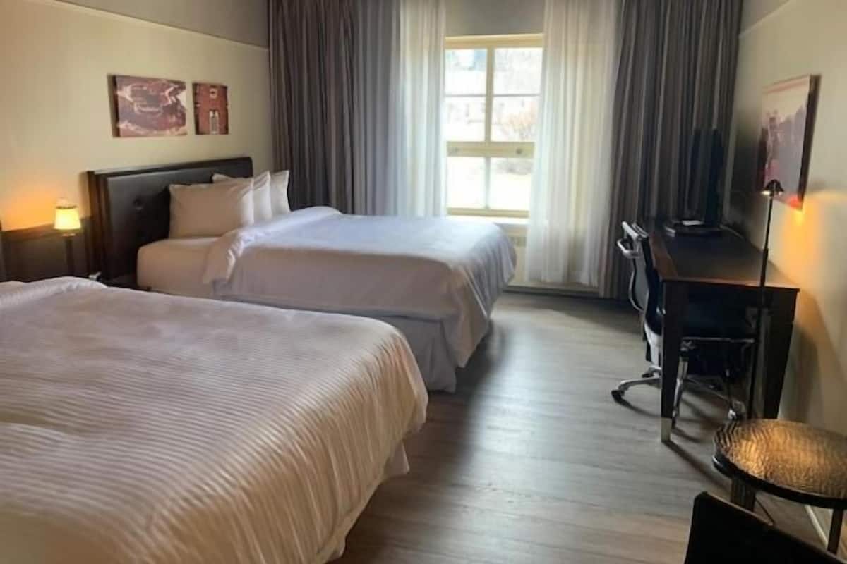 Een hotelkamer met twee bedden, een bureau en een stoel.