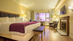 Una habitación de hotel con una cama grande, un escritorio, una silla y una chimenea.