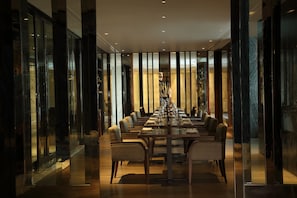 A formal dining room with a long table set for a meal, flanked by glass partitions and wooden panels. - Hyatt Regency Gurgaon (Gurugram)