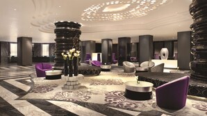Een moderne lobby met een patroon vloer, meerdere zithoeken en een centrale decoratieve kolom.