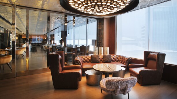 Een moderne lounge met lederen zitplaatsen, een ronde tafel en een bijzondere hanglamp.