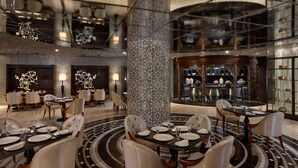Een moderne hotellobby met verschillende eetgedeeltes, een decoratieve centrale kolom en een bar.