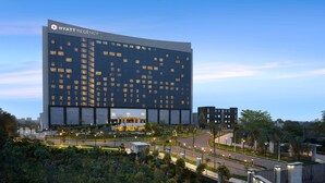 A modern Hyatt Regency hotel with a large glass facade, surrounded by landscaped areas and a well-lit parking structure. - Hyatt Regency Gurgaon (Gurugram)