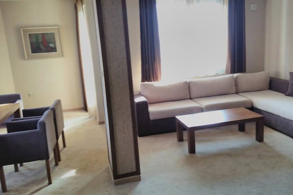Uma sala de estar com sofá, mesa de centro e uma área de jantar com cadeiras.