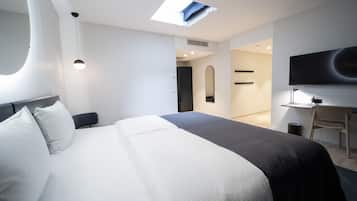 Una habitación de hotel moderna con una cama grande, un escritorio, una silla, un televisor y un tragaluz.