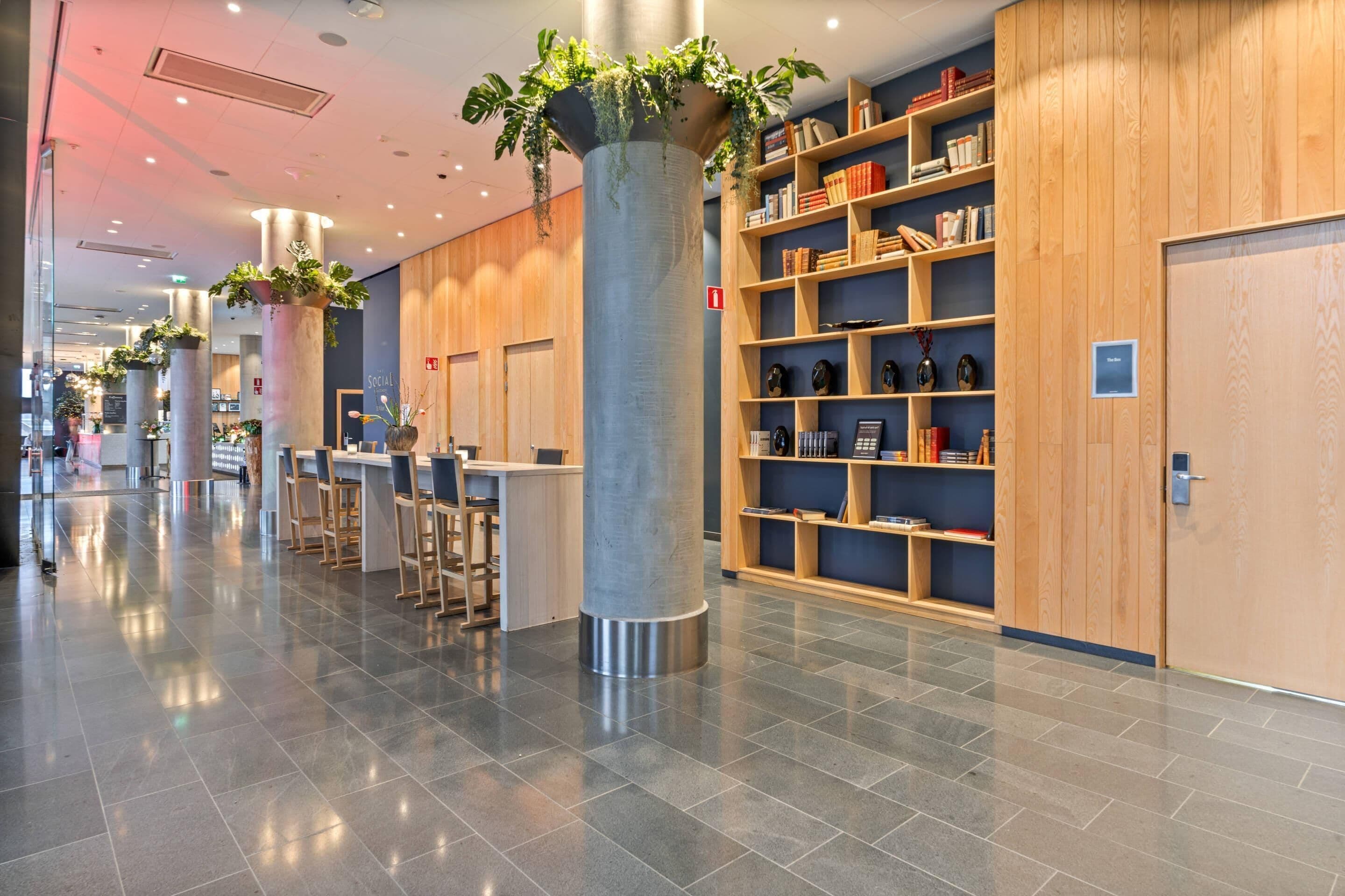 Ein modernes Bibliotheken-Interieur mit Bücherregalen, Sitzbereichen und Zierpflanzen.