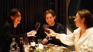 Un grupo de personas brindando con copas de vino en una mesa de cena con diversos platos y bebidas.