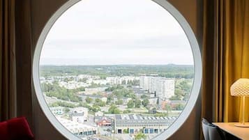 Una ventana redonda con vistas a un paisaje urbano, con edificios y zonas verdes.