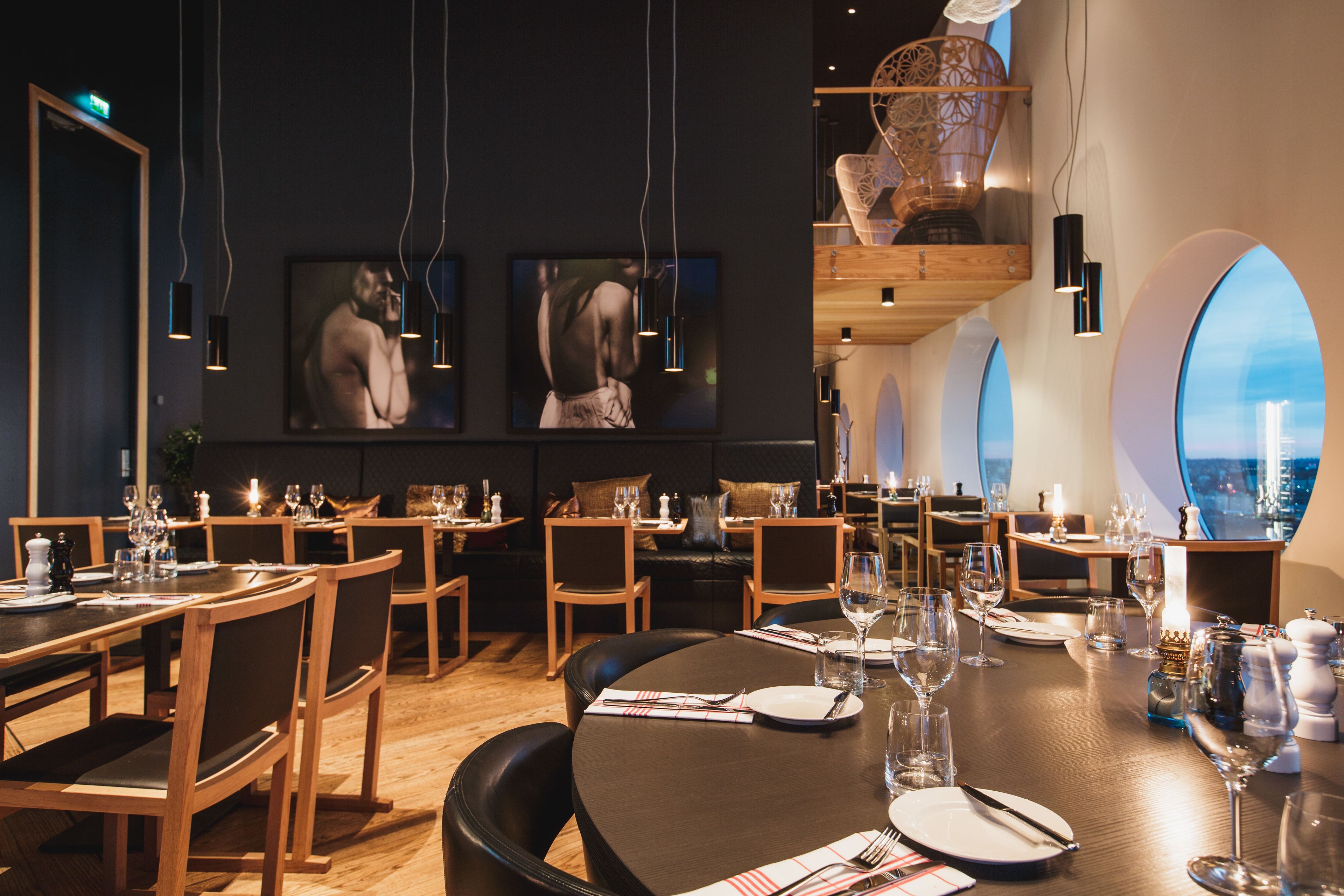A restaurant with round tables, wooden chairs, and modern decor.
