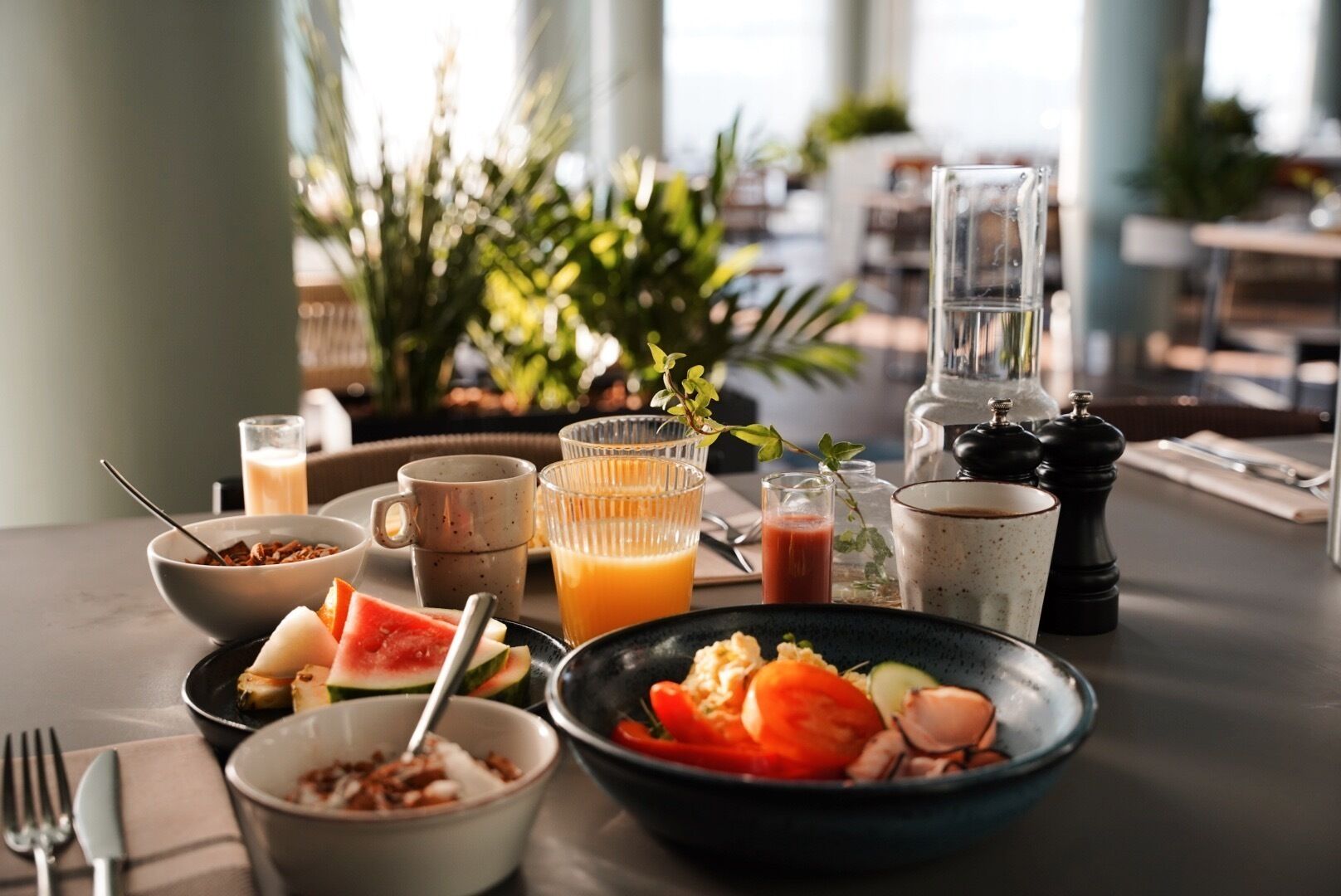A breakfast table with various dishes, drinks, and condiments.