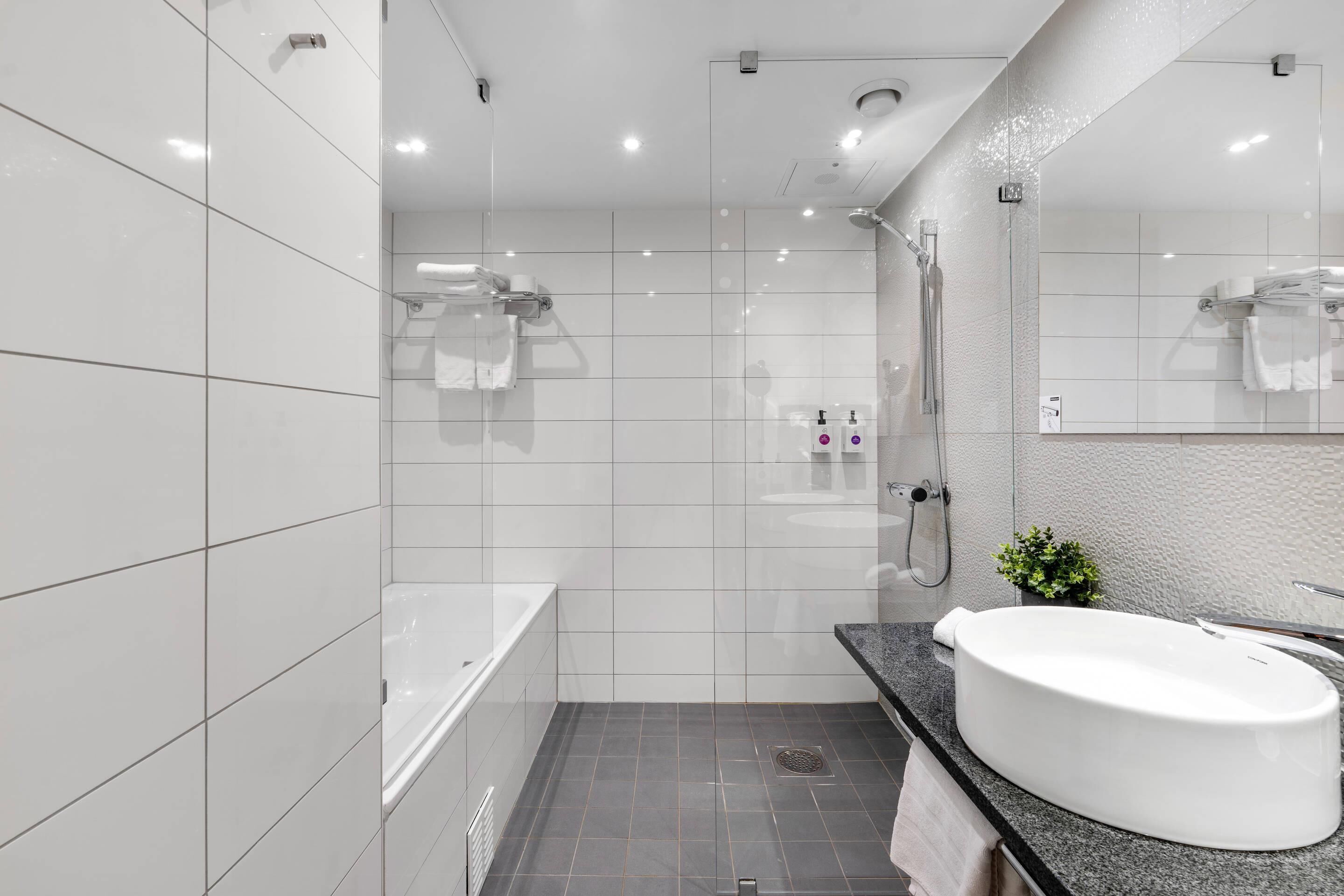 A modern bathroom with a large bathtub, a shower, and a sink.