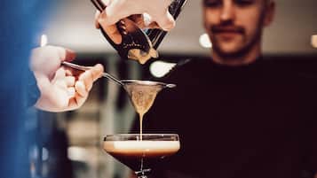 Une personne qui verse une boisson dans un verre à martini.