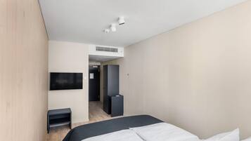 Una habitación de hotel moderna con una cama, televisión, escritorio y armario.
