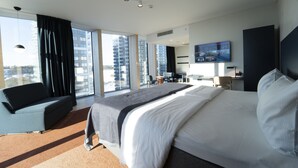 A modern hotel room with a large bed, a sofa, a desk, and a TV. - Quality Hotel Strawberry Arena (Solna)