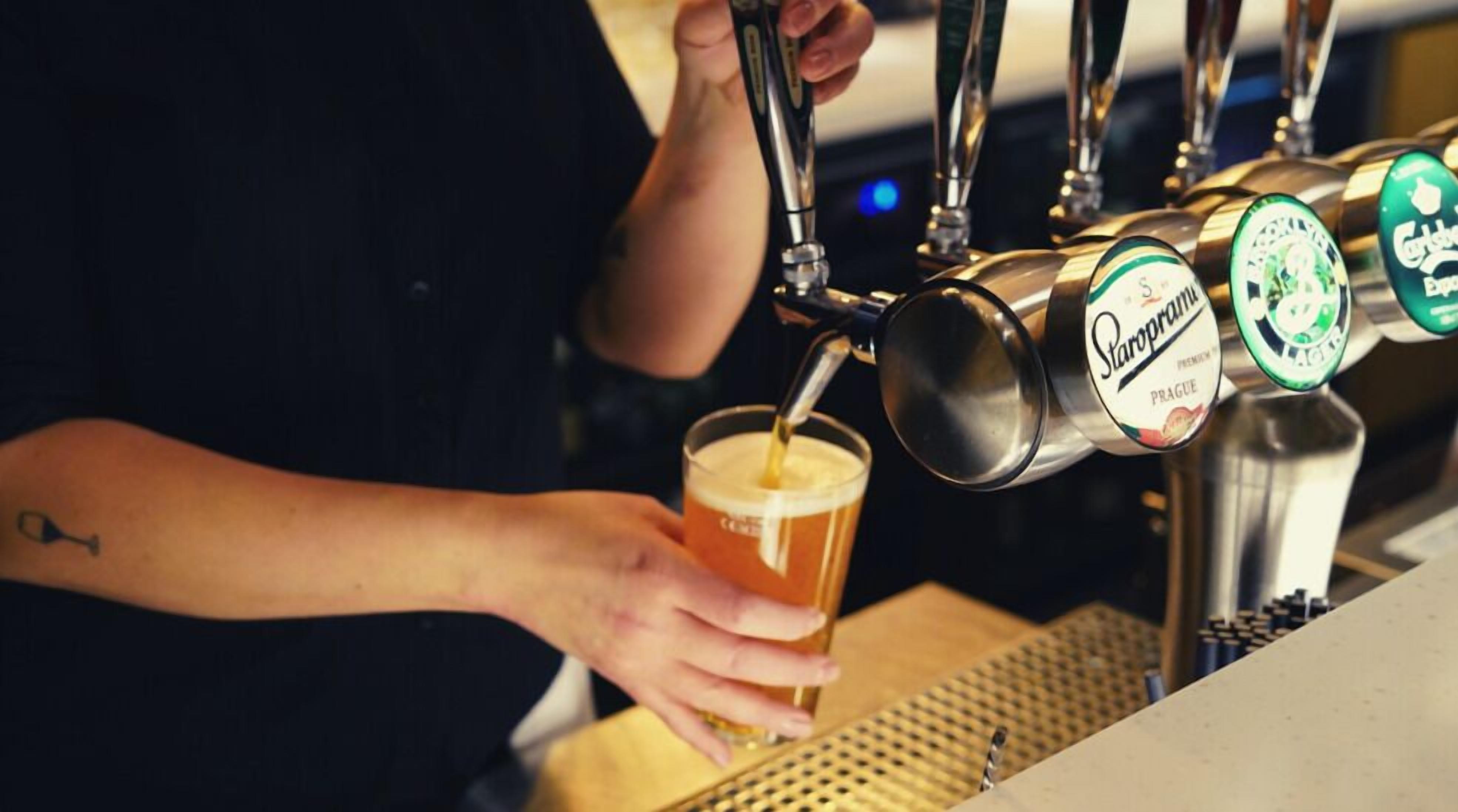 Eine Person zapft Bier in ein Glas.