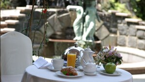 A table set for breakfast with a teapot, cups, a glass of orange juice, a croissant, and a green apple. - Old Continent Hotel (Uzhhorod)
