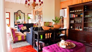 Una sala de estar acogedora con un sofá negro, un reposapiés a rayas de colores y una mesa de centro de madera con cestas.