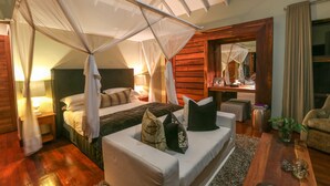 Un dormitorio con cama con dosel, un sofá, una mesita de centro y un espejo.
