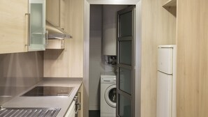 A compact kitchen with a built-in washing machine, a refrigerator, and a stainless steel sink. - Villarroel Apartments Barcelona (Barcelona)
