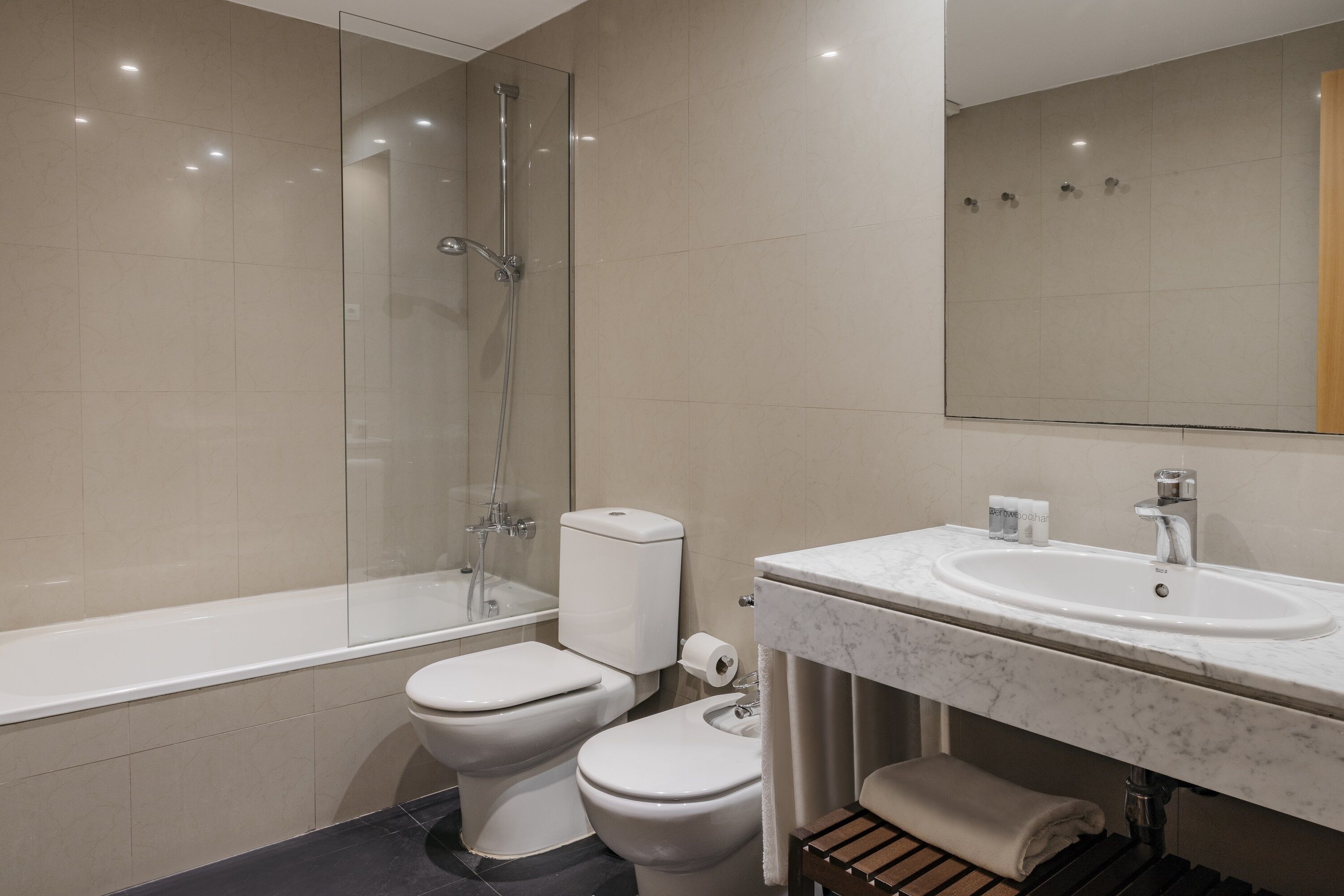 Un bagno moderno con doccia vetrata, un water bianco e un lavabo in marmo.