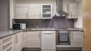 A modern kitchen with light wood cabinetry, a built-in microwave, a dishwasher, and an oven. - Villarroel Apartments Barcelona (Barcelona)