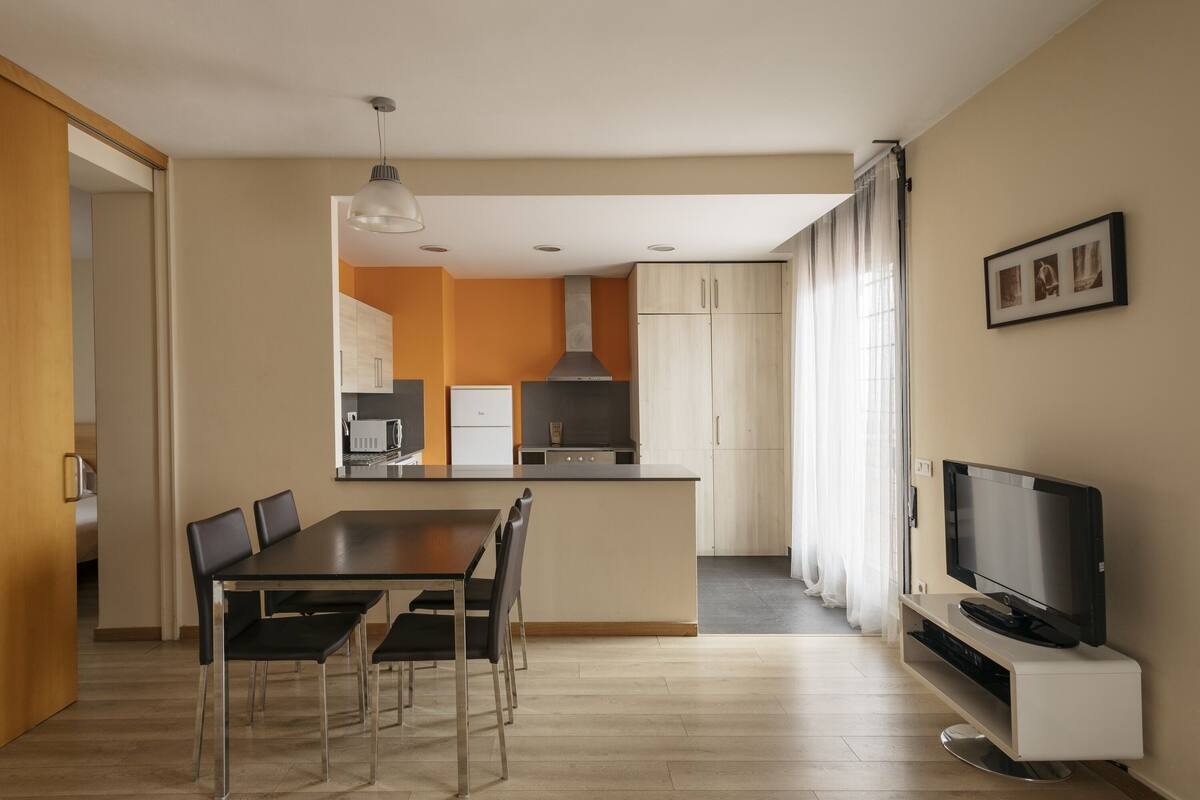 A modern kitchen with a dining area and a TV.