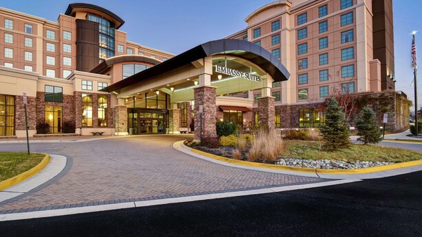 A hotel with a modern design, featuring a prominent entrance with a curved roof and a sign that reads "EMBASSY SUITES."