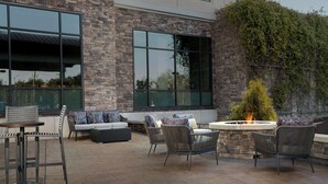 An outdoor patio with wicker furniture, a fire pit, and a stone wall.
