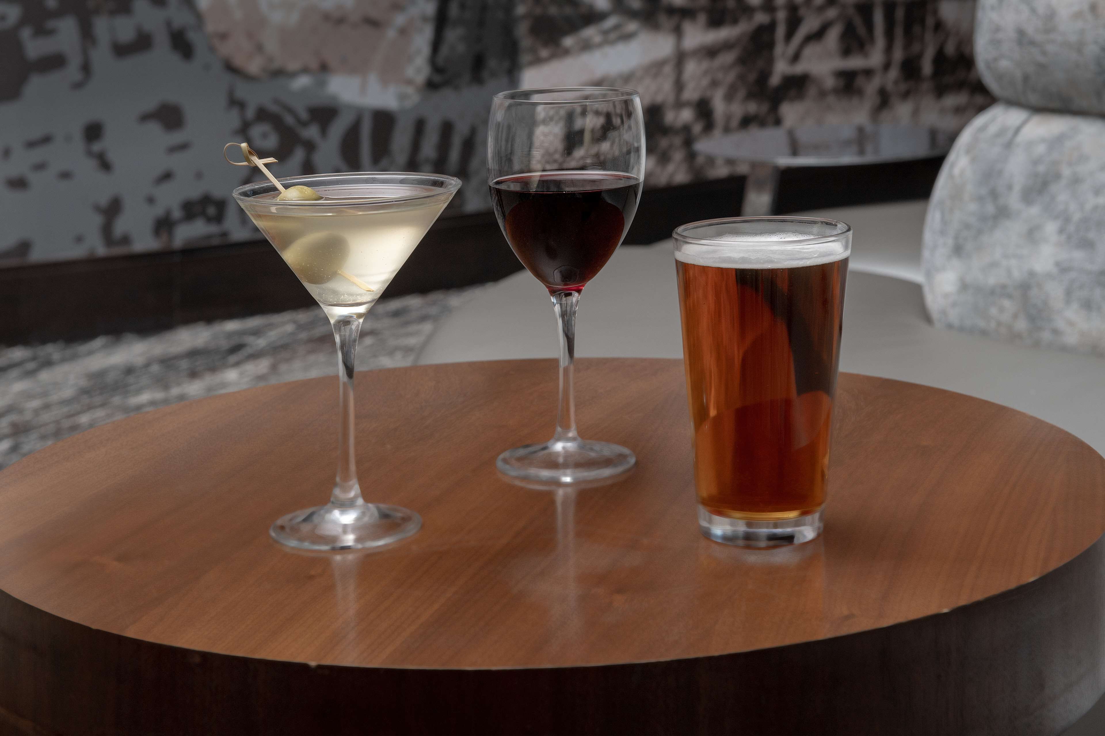 Three glasses of beverages on a round wooden table.